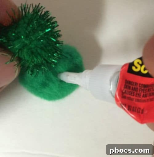 Gluing green pom-poms onto pudding container lids as pumpkin stems, showing glue application