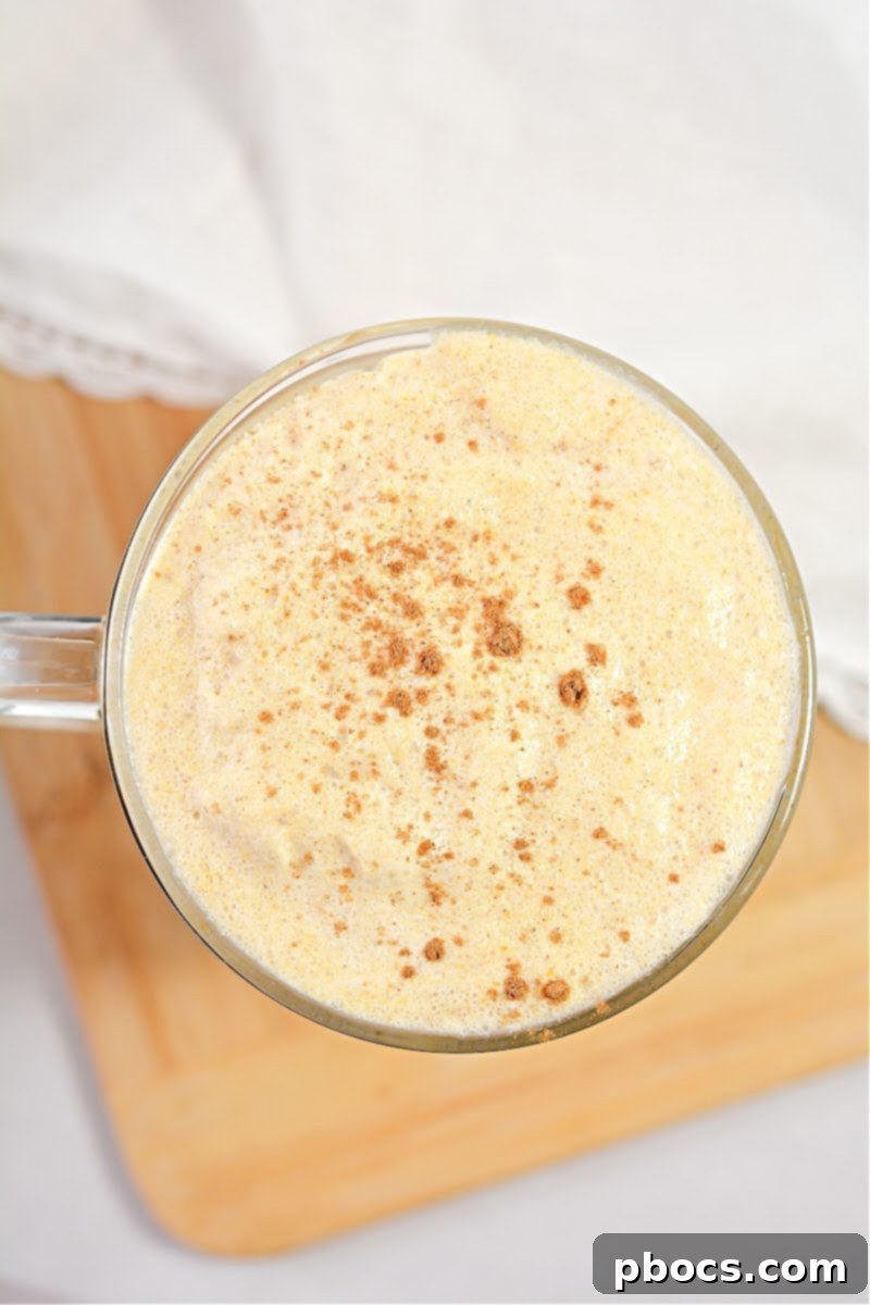 A glass of Keto Pumpkin Cream Cold Brew, garnished with cinnamon, on a wooden surface.
