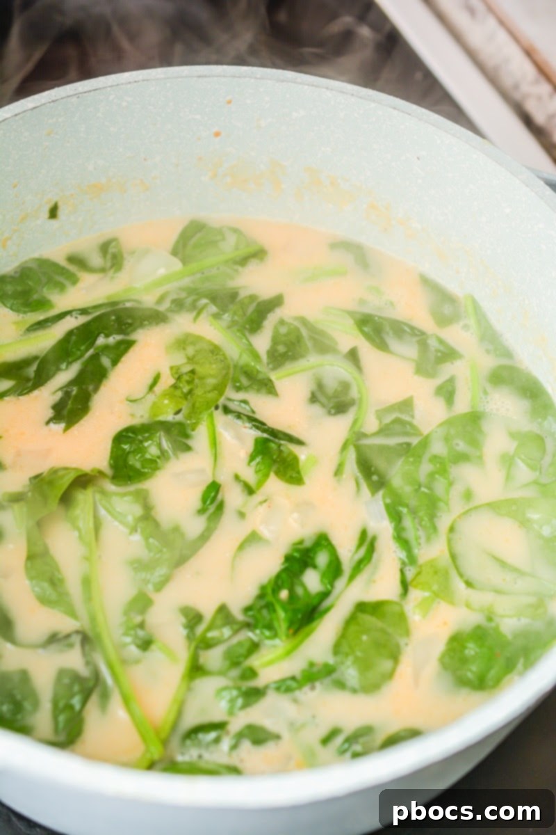 Stirring fresh spinach into the simmering Thai soup until wilted