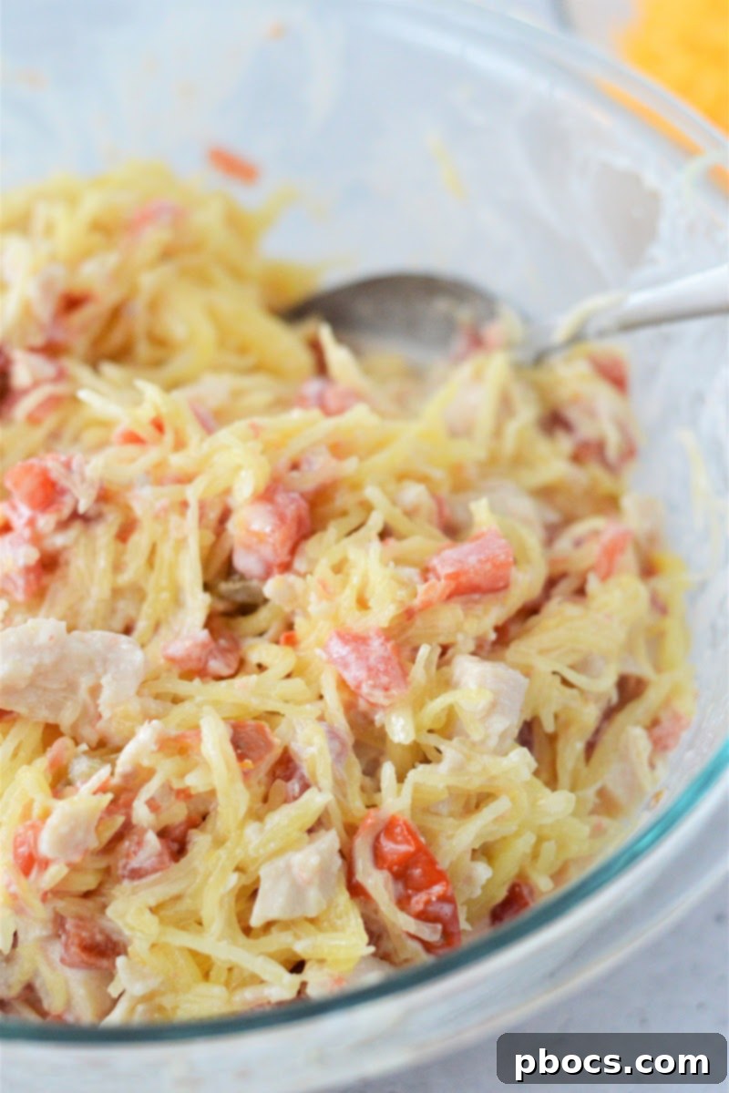 Combining chicken, spaghetti squash, and sauce for baking