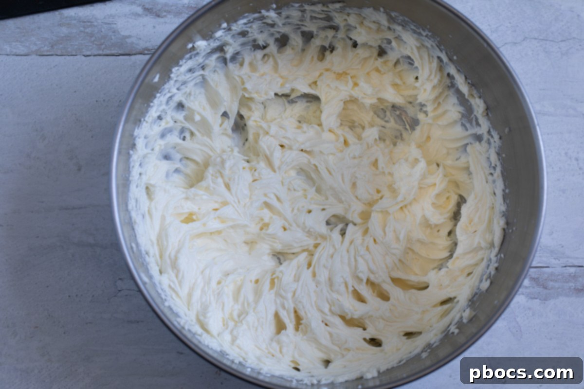 Heavy whipping cream being beaten in a stand mixer, showing the start of stiff peaks forming.