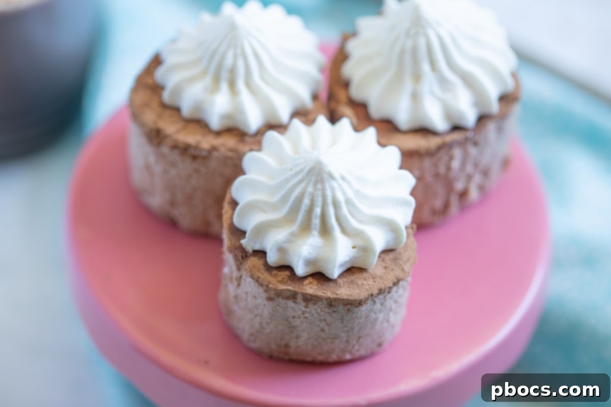 Four Keto Hot Chocolate Fat Bombs arranged neatly on a white plate, each topped with whipped cream, ready to be enjoyed.