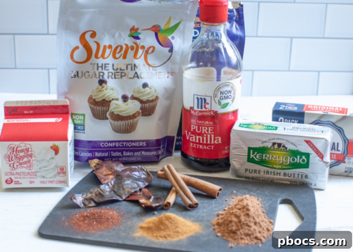 A flat lay of ingredients for Keto Hot Chocolate Fat Bombs, including cream cheese, butter, erythritol, cocoa powder, vanilla, cinnamon, and chili powder.