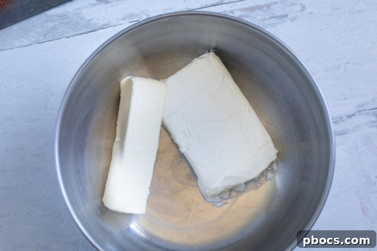 A mixing bowl with beaten cream cheese and butter, appearing light and fluffy.