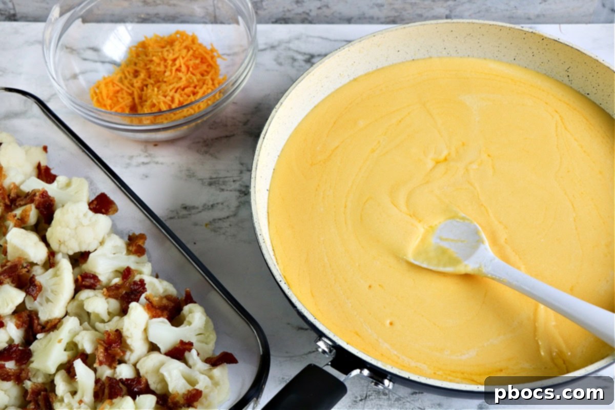 Close-up of the creamy cheese sauce being poured over the cauliflower and bacon.