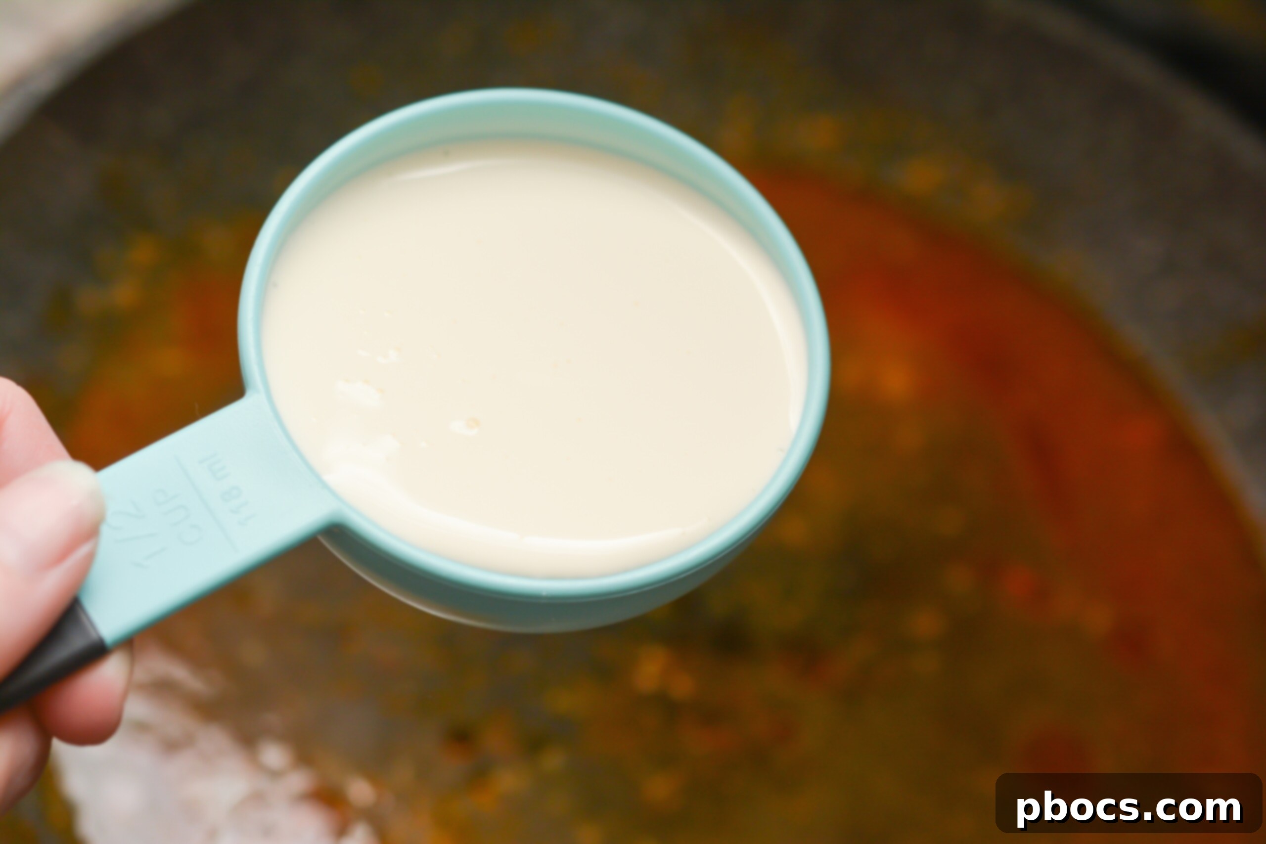 Step 6: Pouring in chicken broth and heavy whipping cream to create the sauce base.