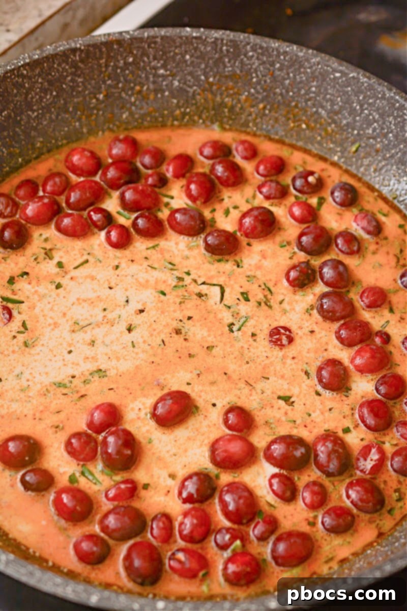 Step 8: Stirring cranberries into the sauce before returning the chicken.