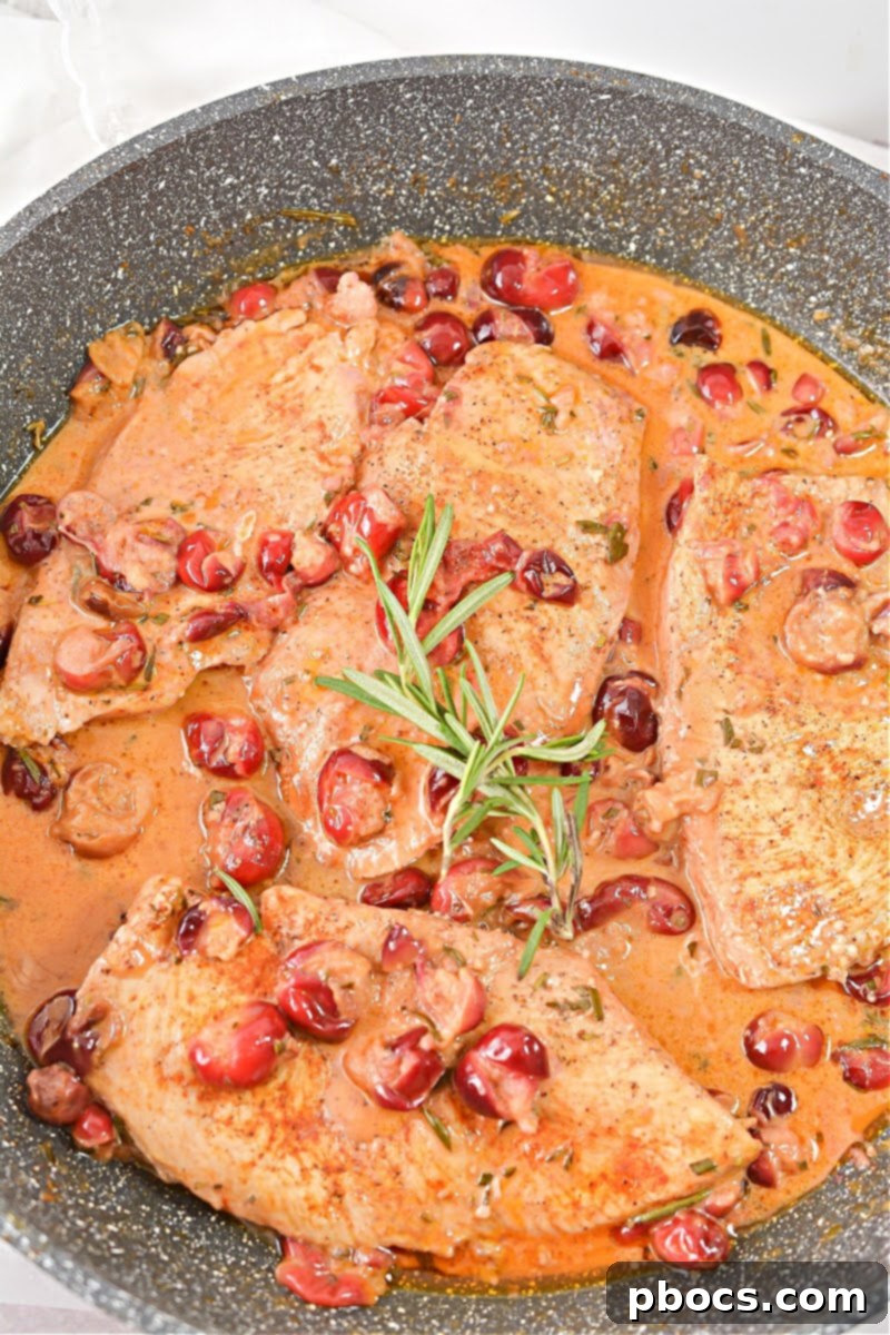 Cooking Creamy Keto Cranberry Rosemary Chicken Skillet in a large skillet, showing the chicken searing.
