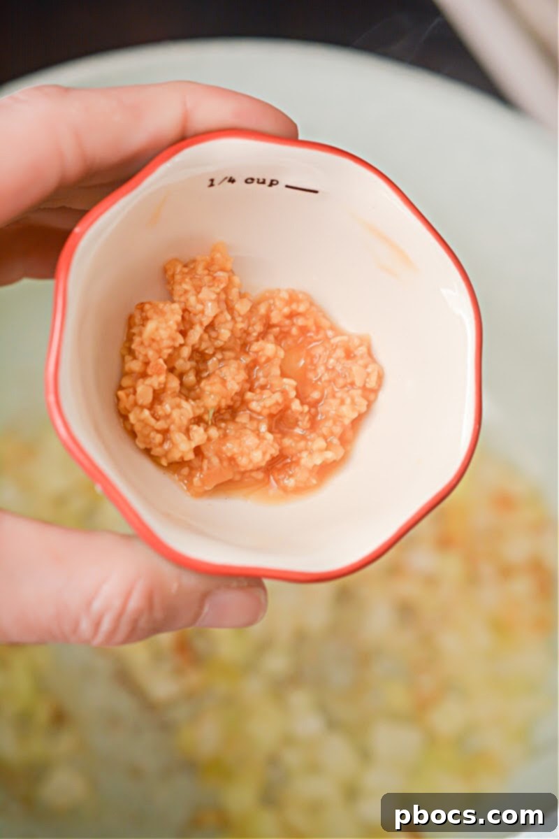 Creamy Keto Chicken Alfredo Soup 11 Adding minced garlic to onions in the pot