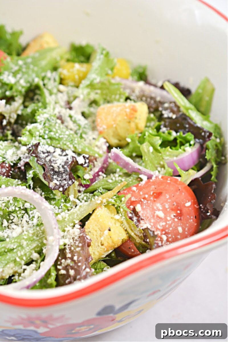 A serving of Keto Copycat Olive Garden Salad in a white bowl, showing the texture of the croutons and dressing, ready to be enjoyed.