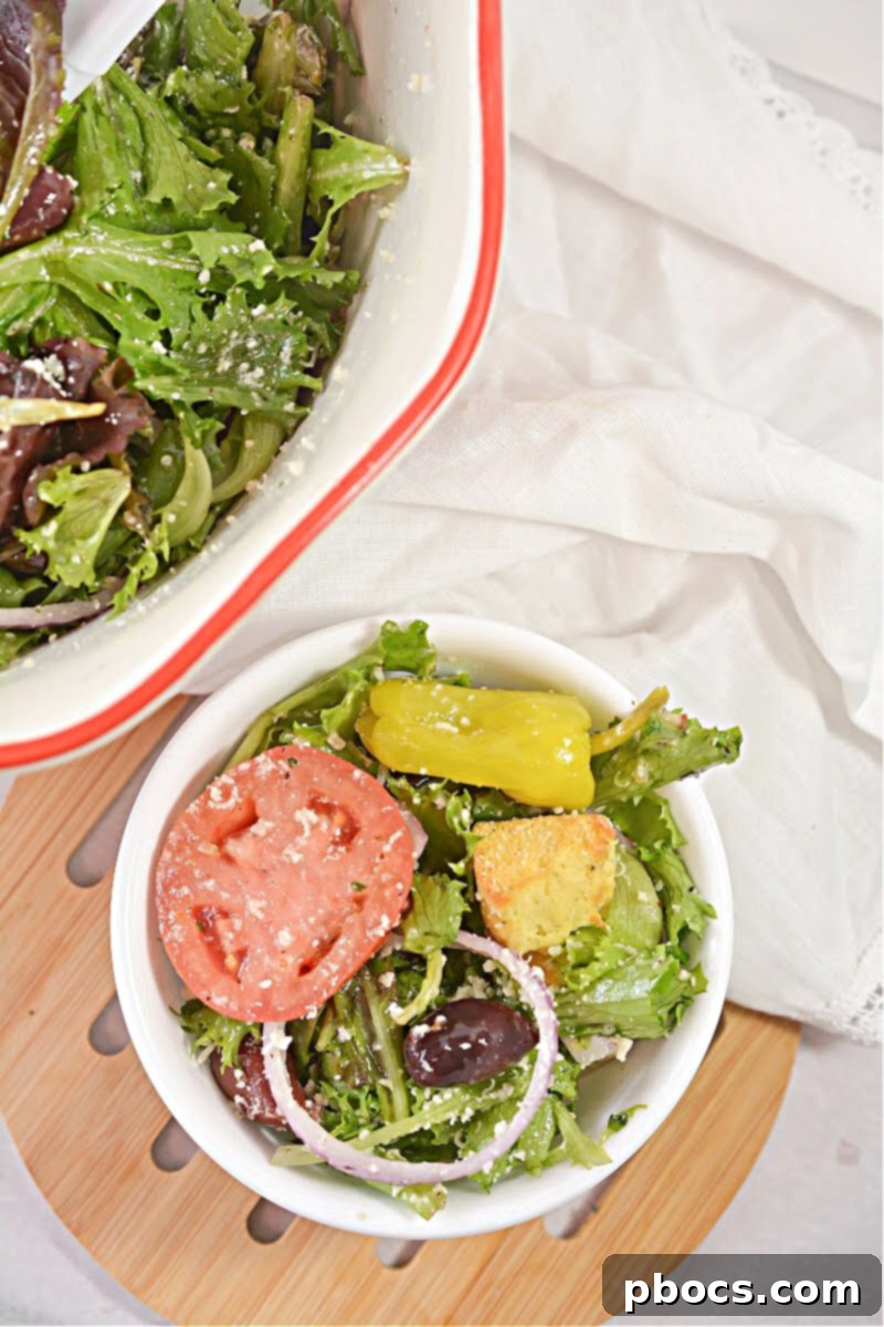 A mason jar filled with freshly made creamy Keto Copycat Olive Garden Dressing, with a whisk beside it, ready for use.