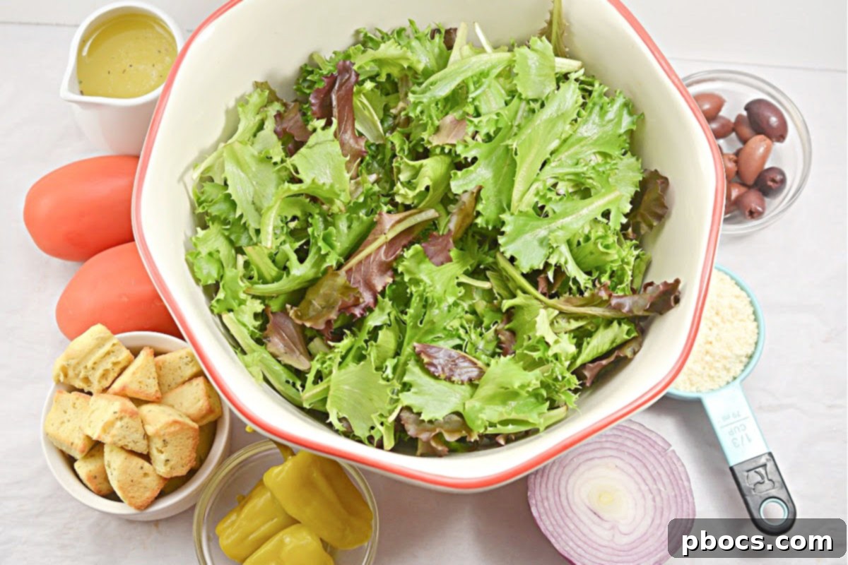 All the ingredients for the Keto Copycat Olive Garden Salad laid out on a cutting board, including fresh vegetables, croutons, and dressing components.