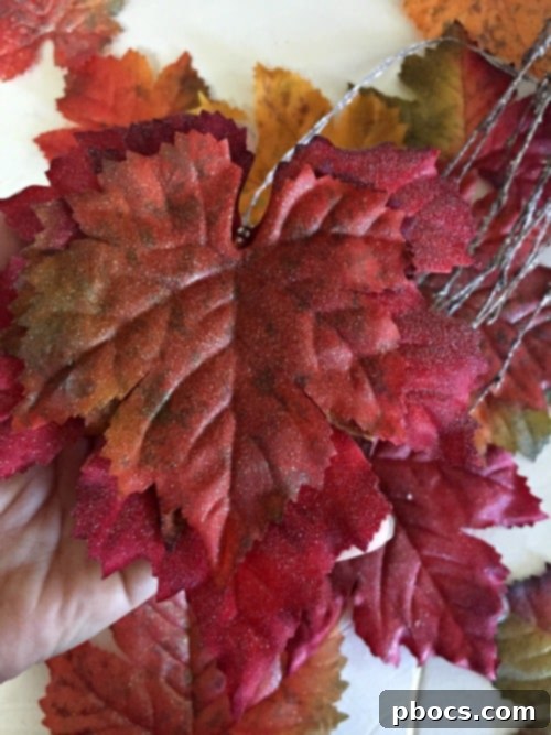 Assembling sparkly leaf garland on a branch
