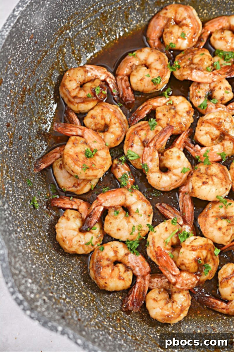 Close-up shot of shrimp perfectly sautéed in a cast-iron skillet, glistening with a slight sear.