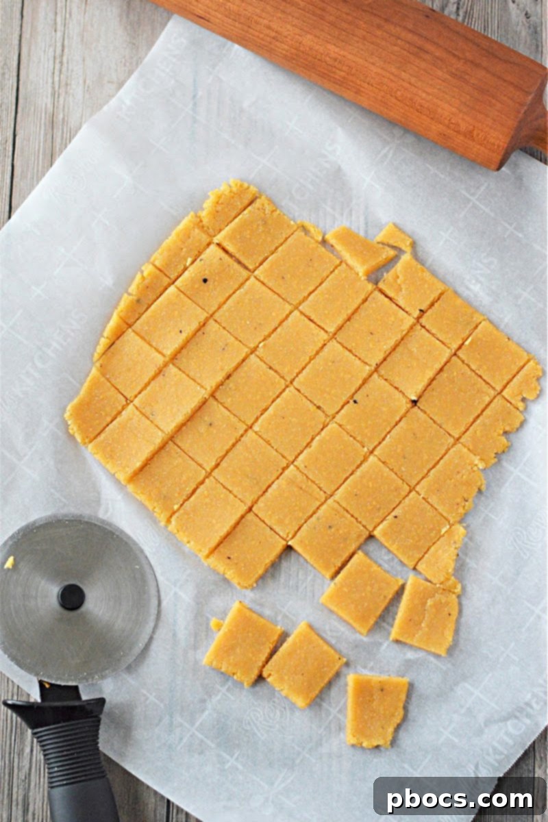 Keto Cheese Cracker dough cut into small squares on parchment paper