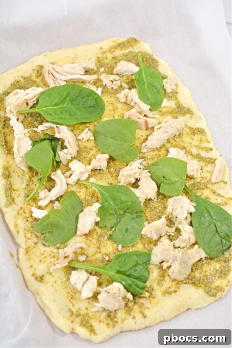 Sprinkling mozzarella and parmesan cheese over the chicken and spinach toppings.