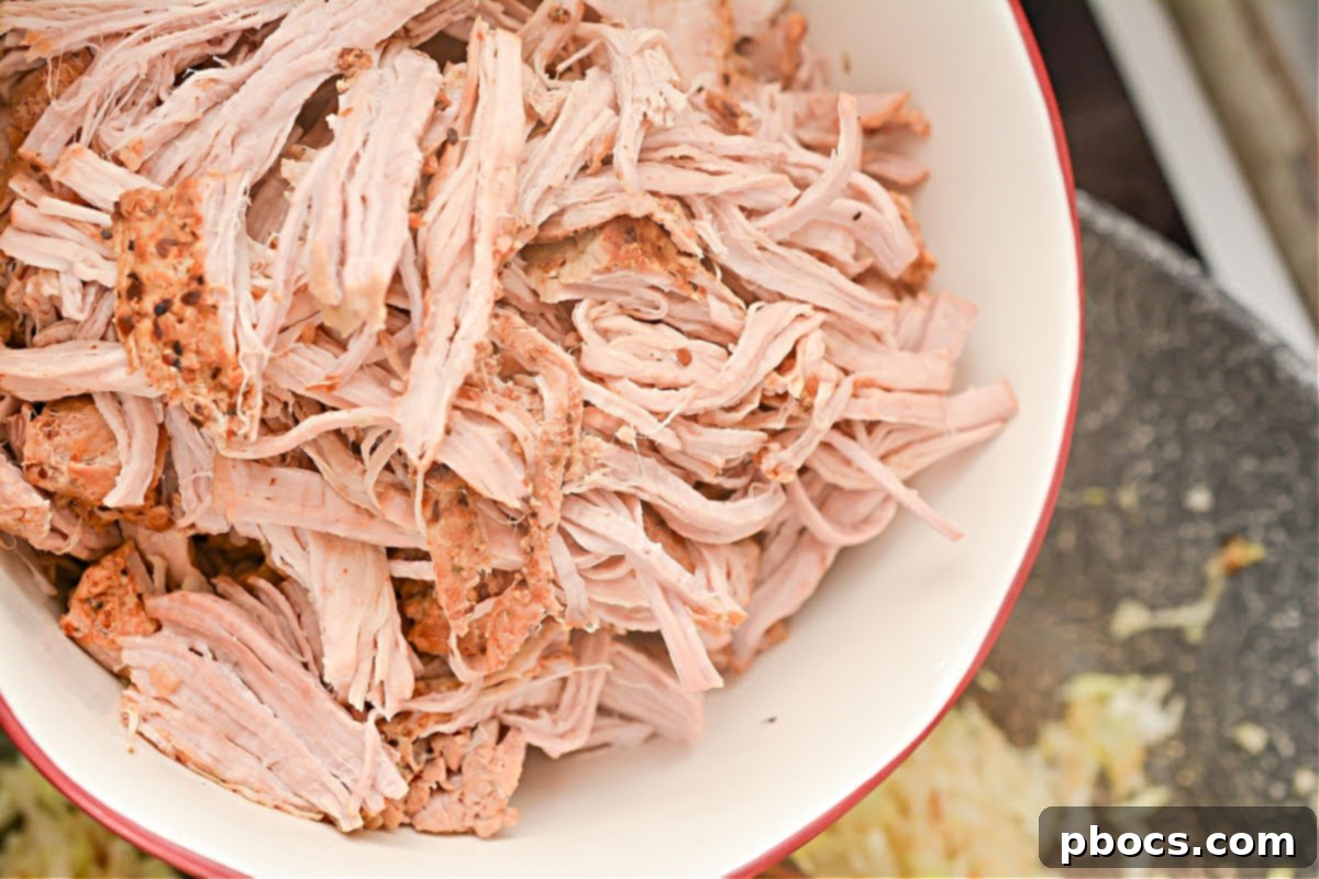 Keto Fiesta Pulled Pork Taco Casserole 11 Mixing pulled pork, seasonings, and enchilada sauce in a skillet