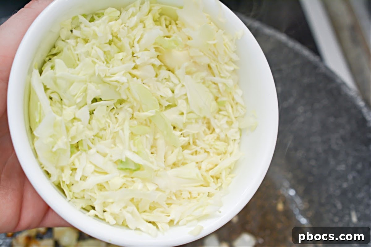 Keto Fiesta Pulled Pork Taco Casserole 10 Adding shredded cabbage to the skillet for casserole filling