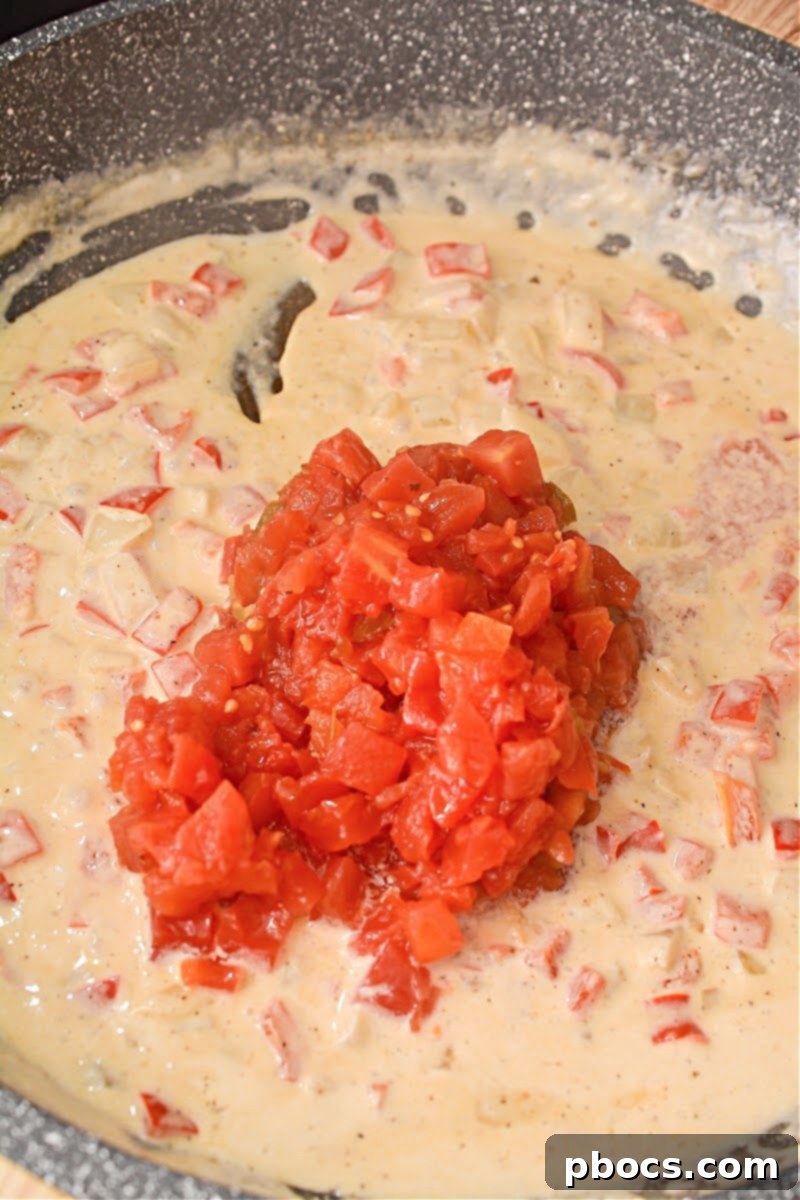 Ro-Tel tomatoes, chicken bouillon powder, salt, and pepper added to the creamy sauce in the skillet, being stirred to combine.