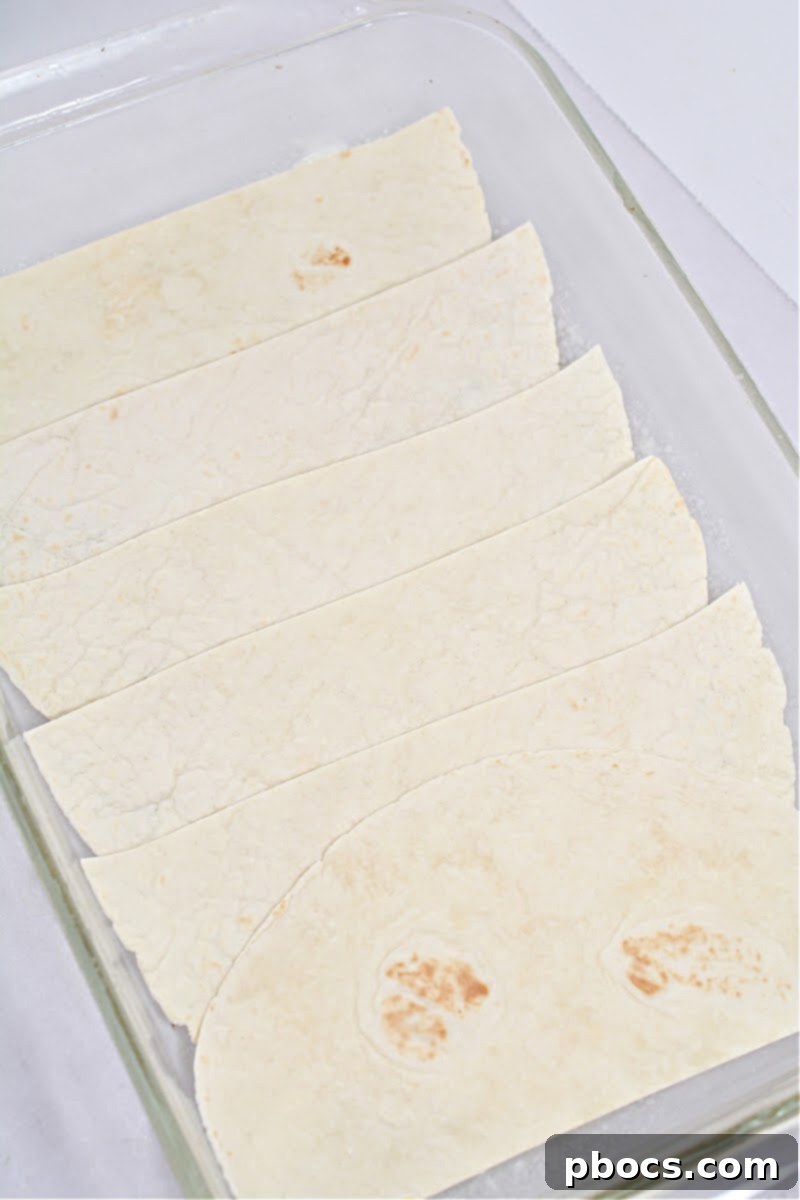 Low-carb tortilla pieces layered at the bottom of a greased 9x13 baking dish, forming the base of the casserole.