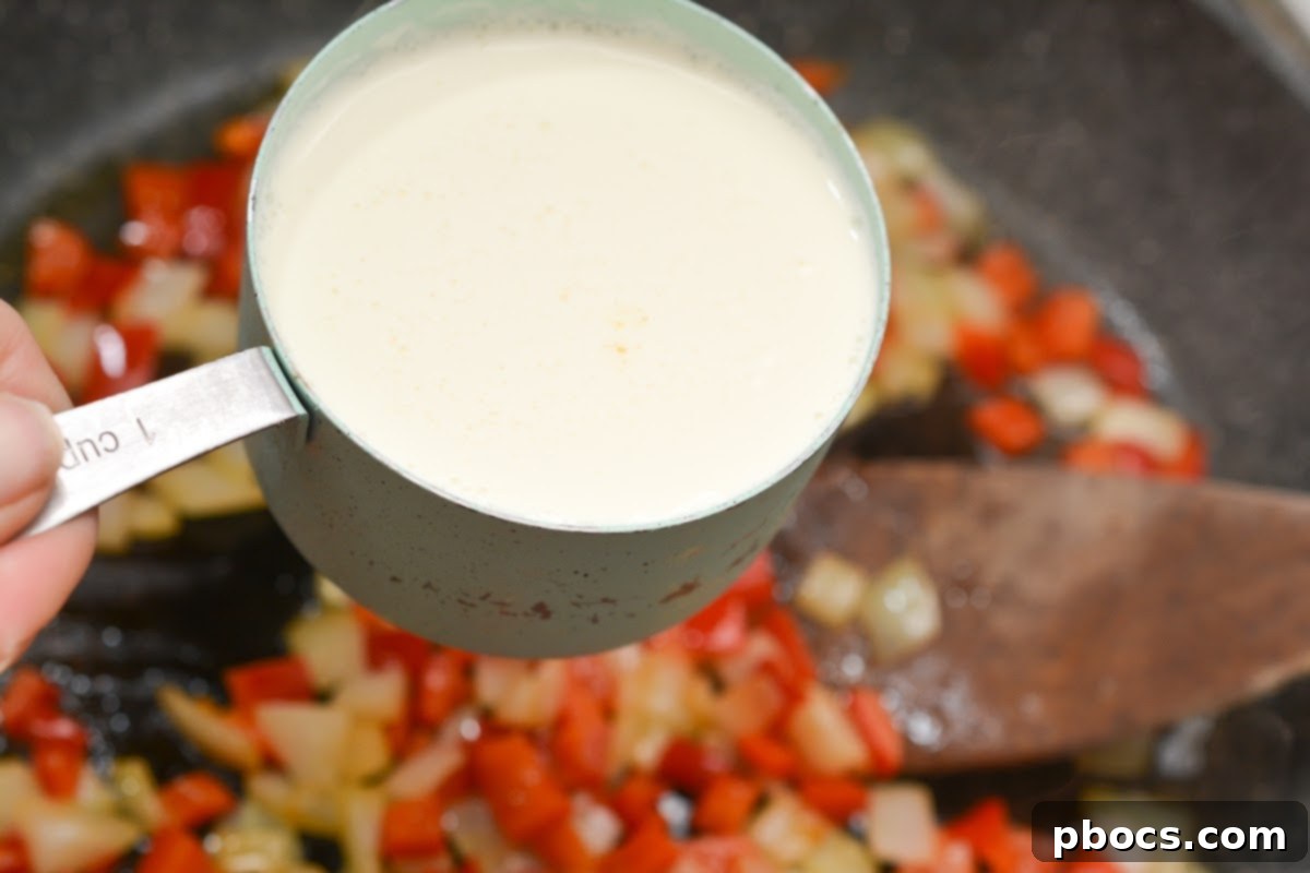 Chopped red bell peppers and onions sautéing in butter in a skillet until tender and fragrant.