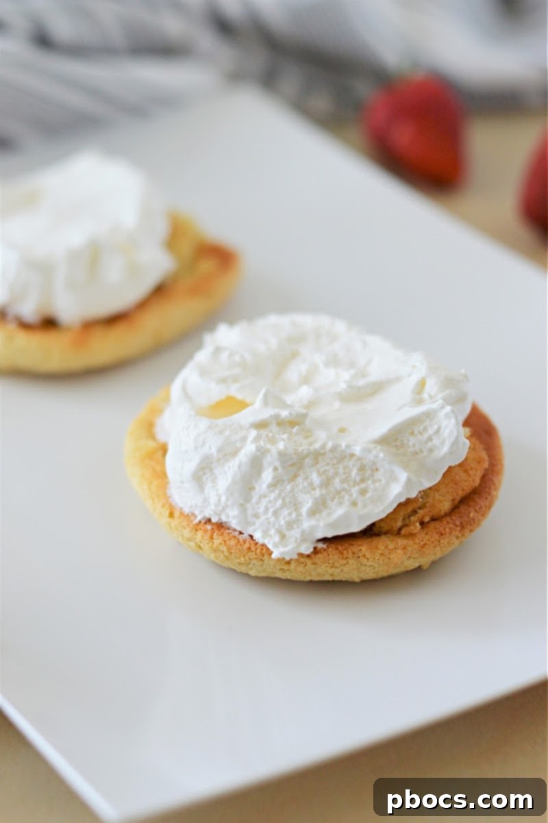 Topping a keto shortcake biscuit with whipped cream