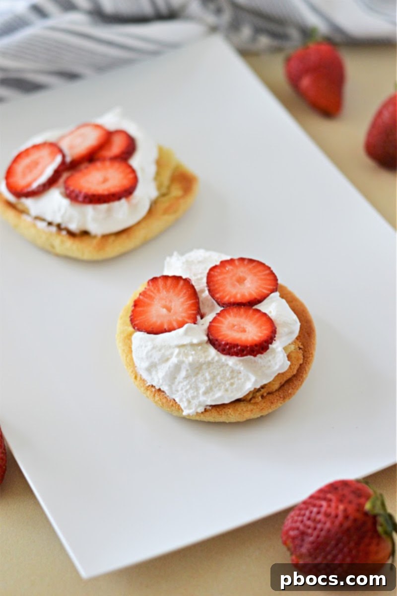 Assembling a Keto Strawberry Shortcake with fresh strawberries and whipped cream