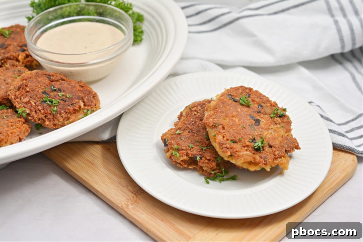 A plate of golden Keto Crab Cakes served with dipping sauce and fresh herbs.