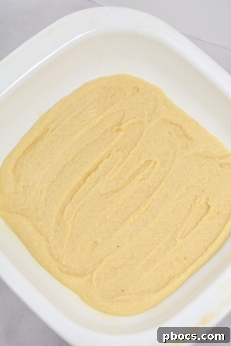 Spreading batter into a baking dish for Keto Raspberry Swirl Cake Bars.