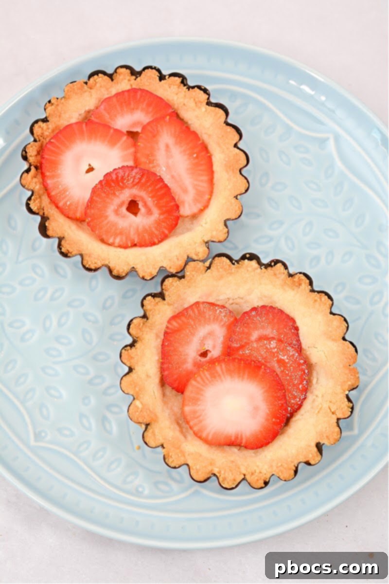 Delicious Keto Strawberry Mini Pies 13 Sliced strawberries being arranged in baked mini pie crusts