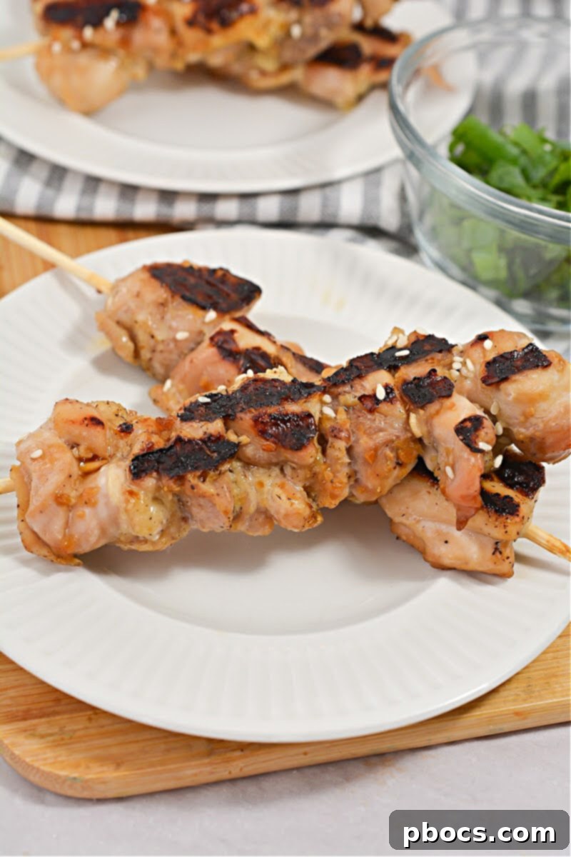 Sticky Keto Chicken Yakitori Skewers 4 Three Keto Chicken Yakitori Skewers arranged on a rustic wooden board
