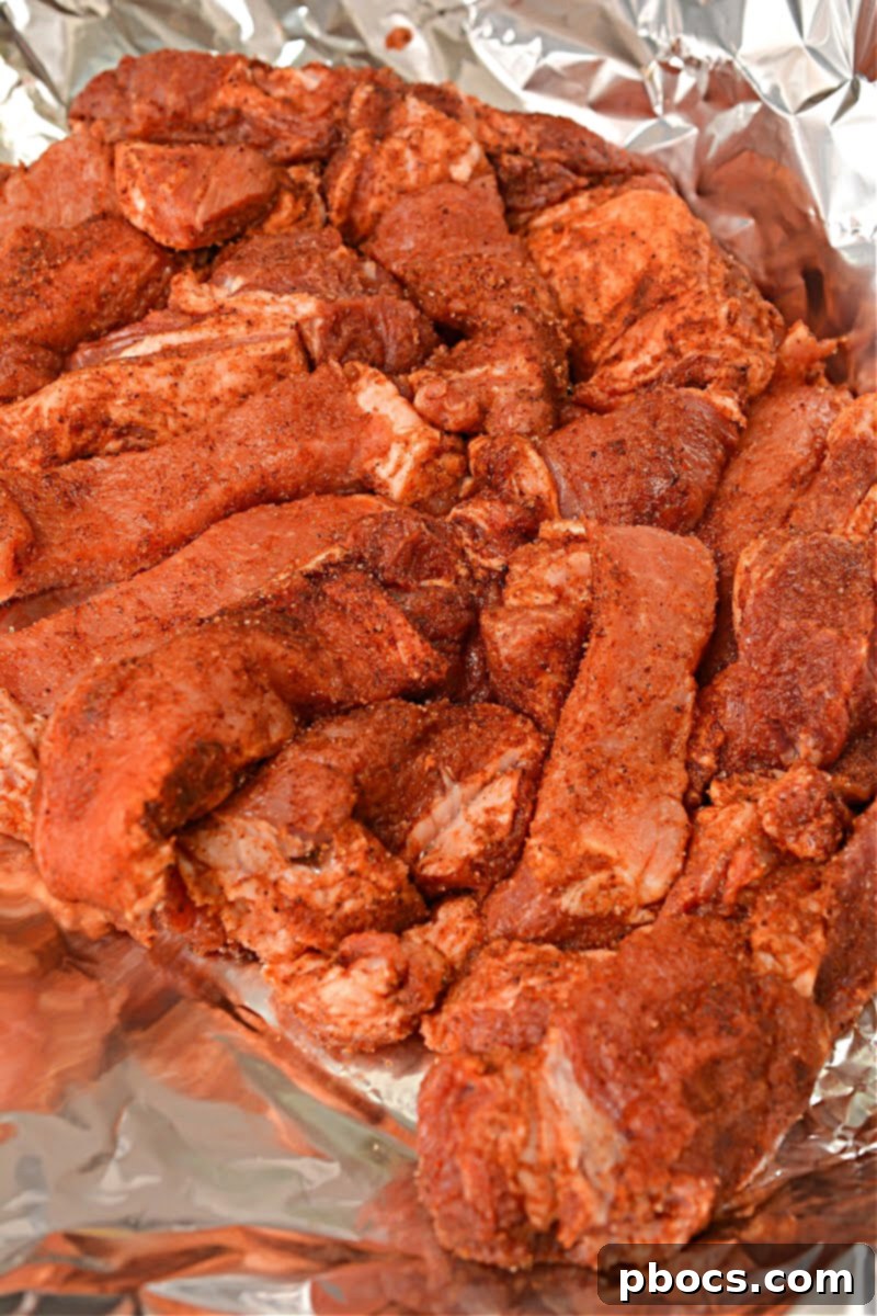 Cajun Keto Oven Ribs 11 Layering seasoned pork ribs on a baking sheet inside foil