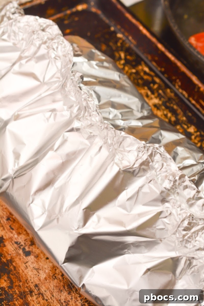 Cajun Keto Oven Ribs 13 Pouring braising liquid over pork ribs in foil packet