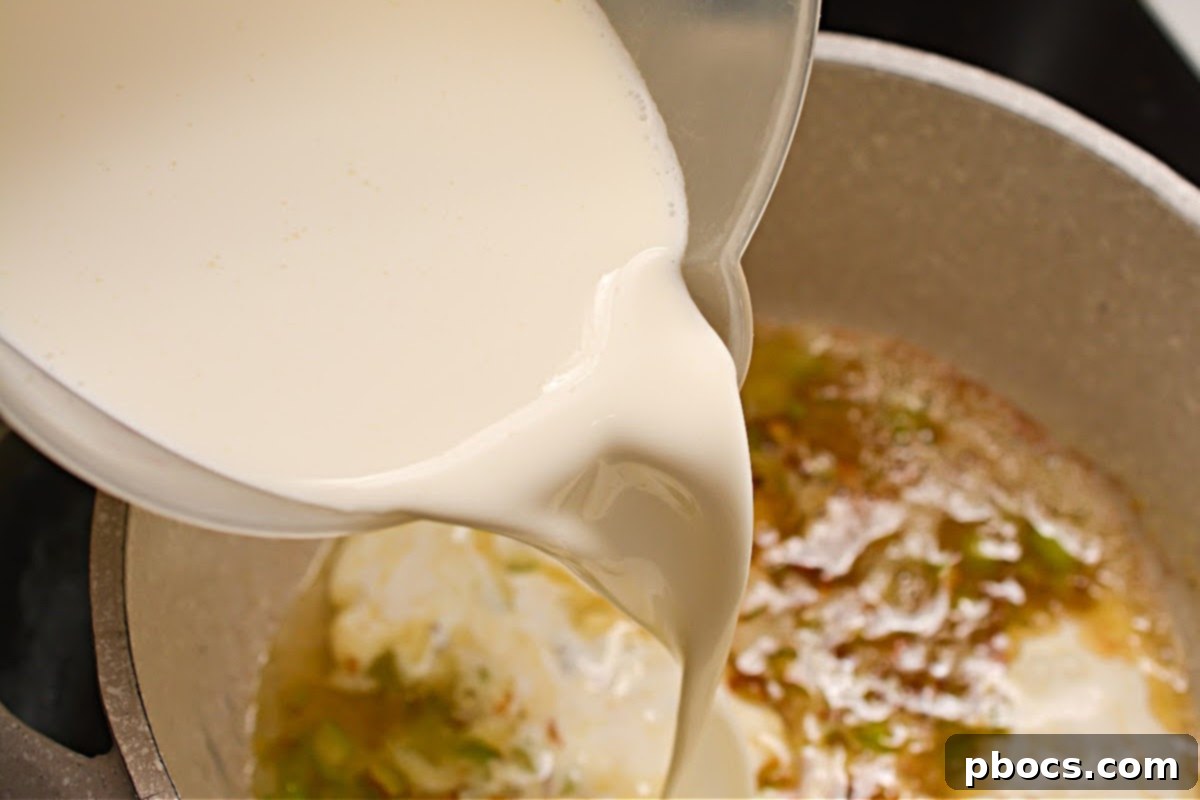Chicken broth and heavy whipping cream poured into the saucepan, beginning to simmer.