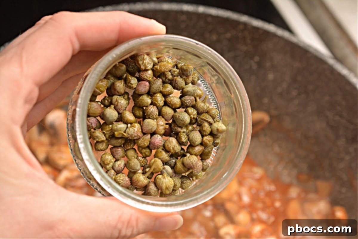 Capers being added to the sauce