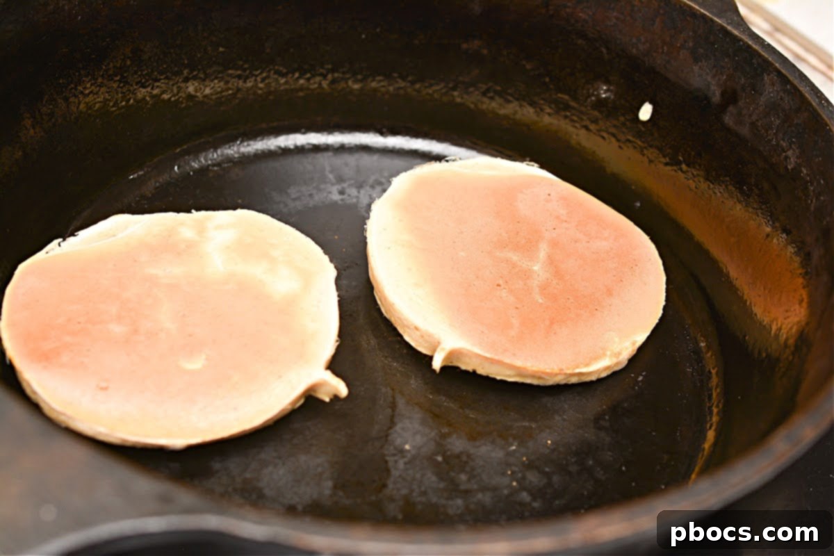 Keto Protein Pancakes Cooking on Skillet with Bubbles Forming