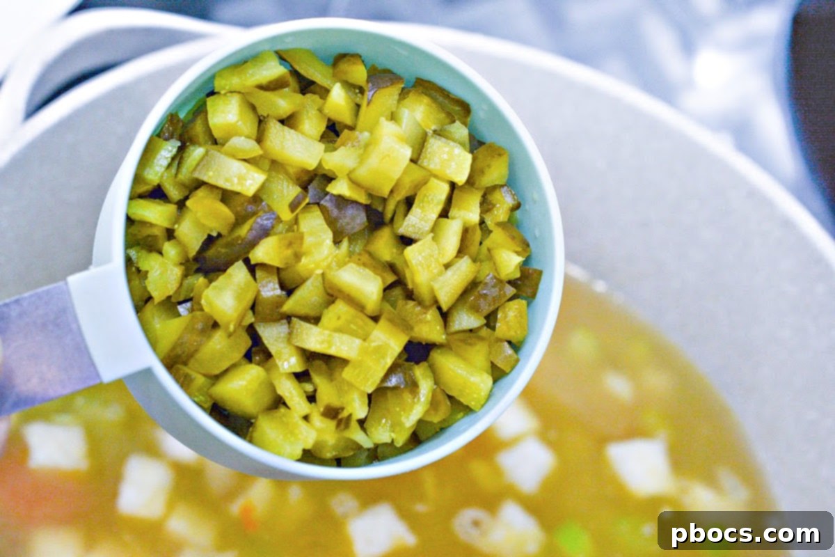 Adding dill pickles and broth to sautéed vegetables