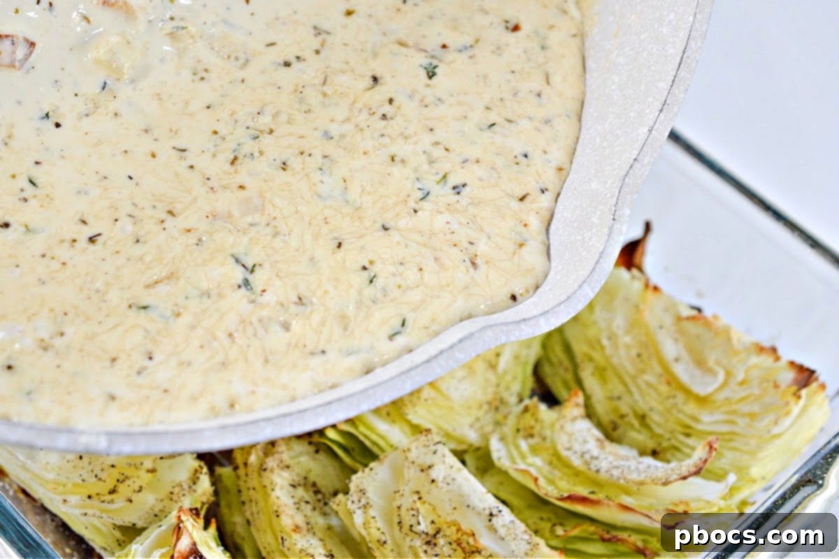 Creamy sauce poured over roasted cabbage in a baking dish