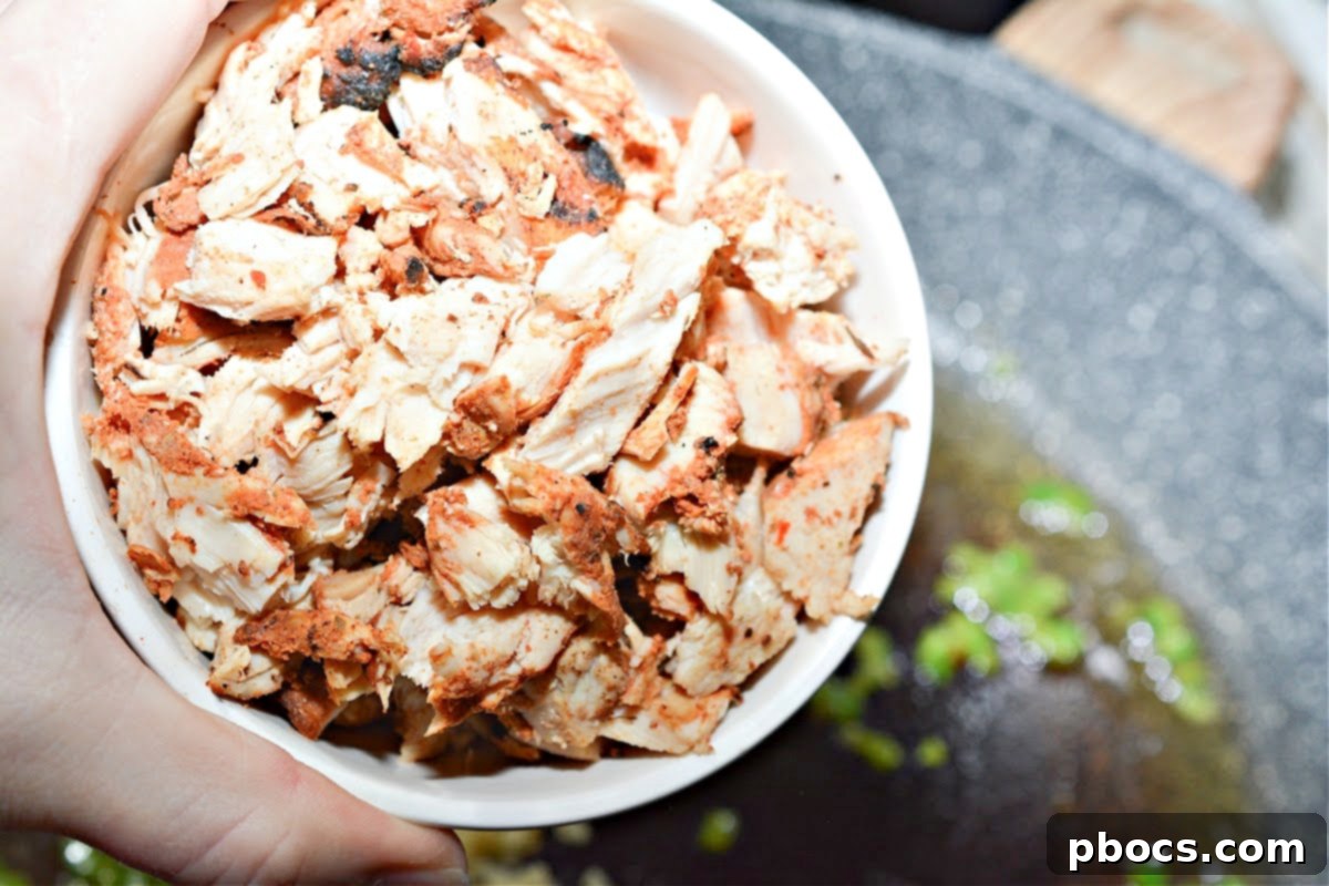 Minced garlic being added to sautéed jalapenos in a skillet.