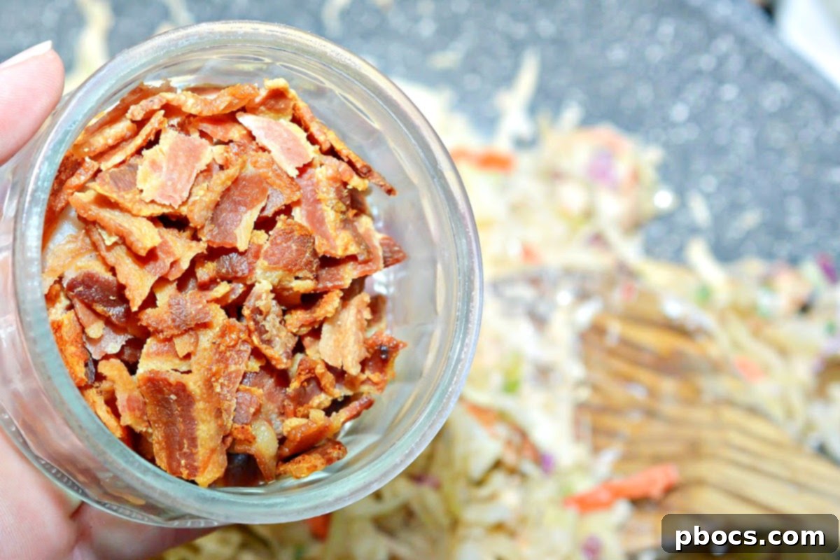 Coleslaw mix being tossed into the creamy chicken mixture in a skillet.