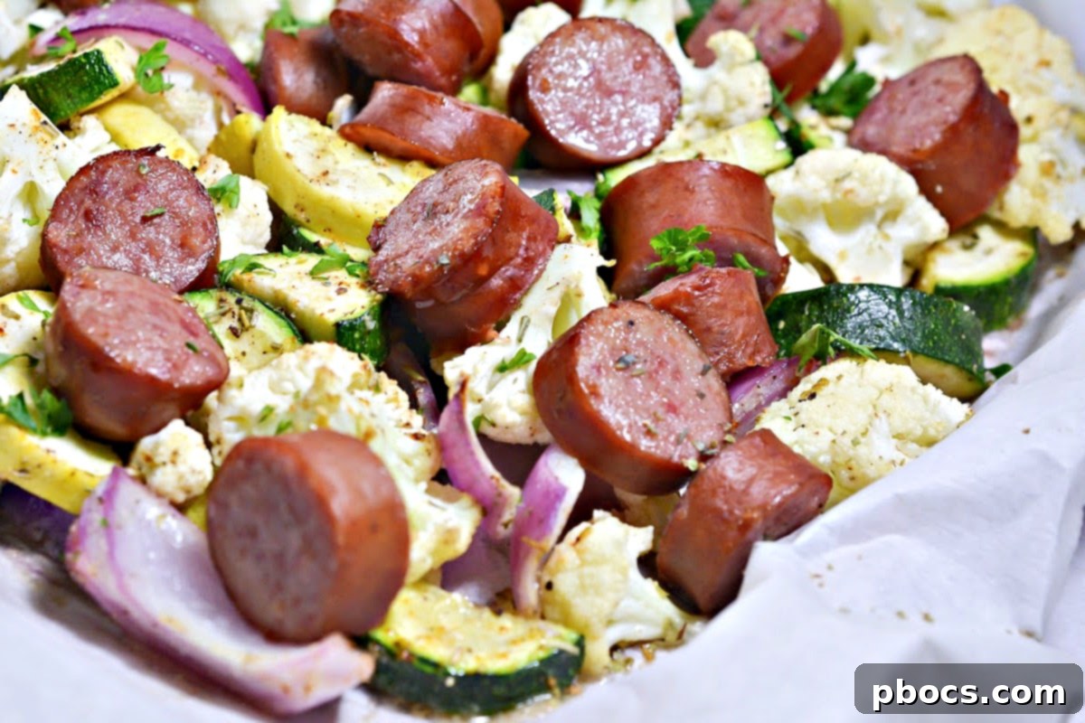 Low-Carb Sheet Pan Sausage and Veggies - Sliced sausage layered over vegetables on a sheet pan