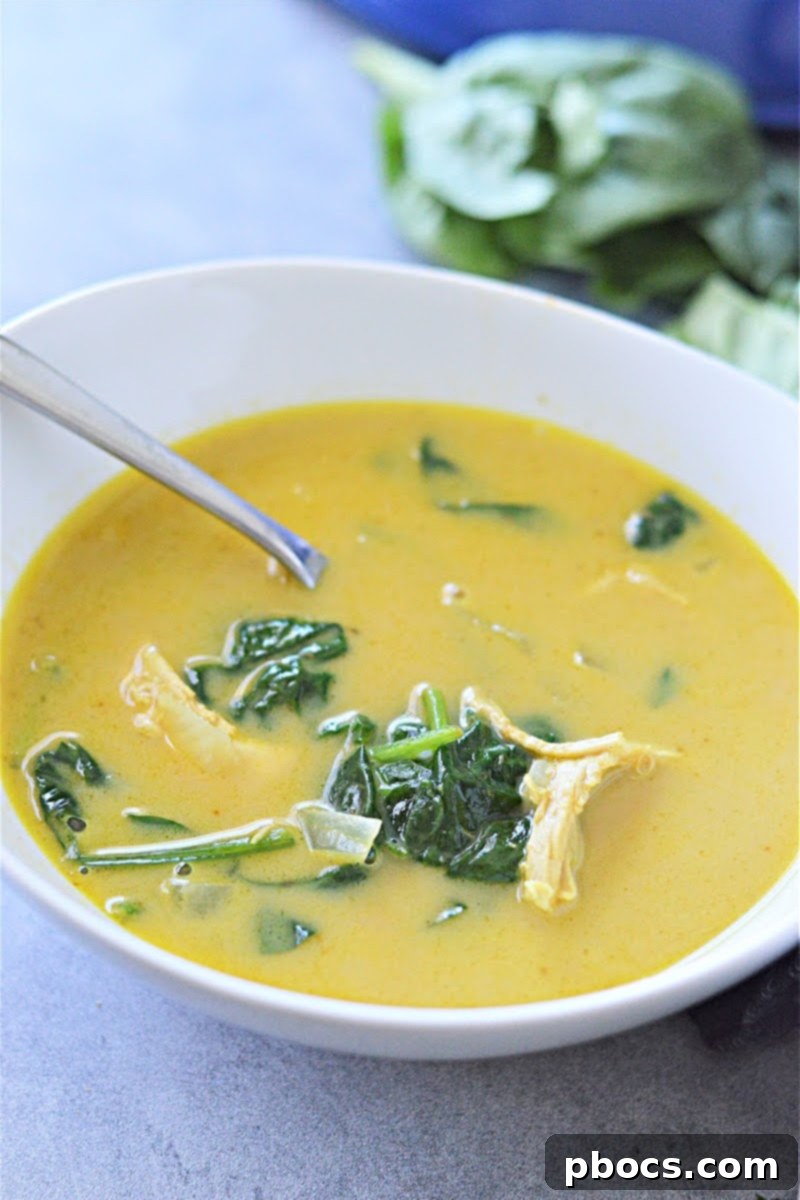 Coconut milk being poured into Creamy Keto Pumpkin Curry Soup for a dairy-free option