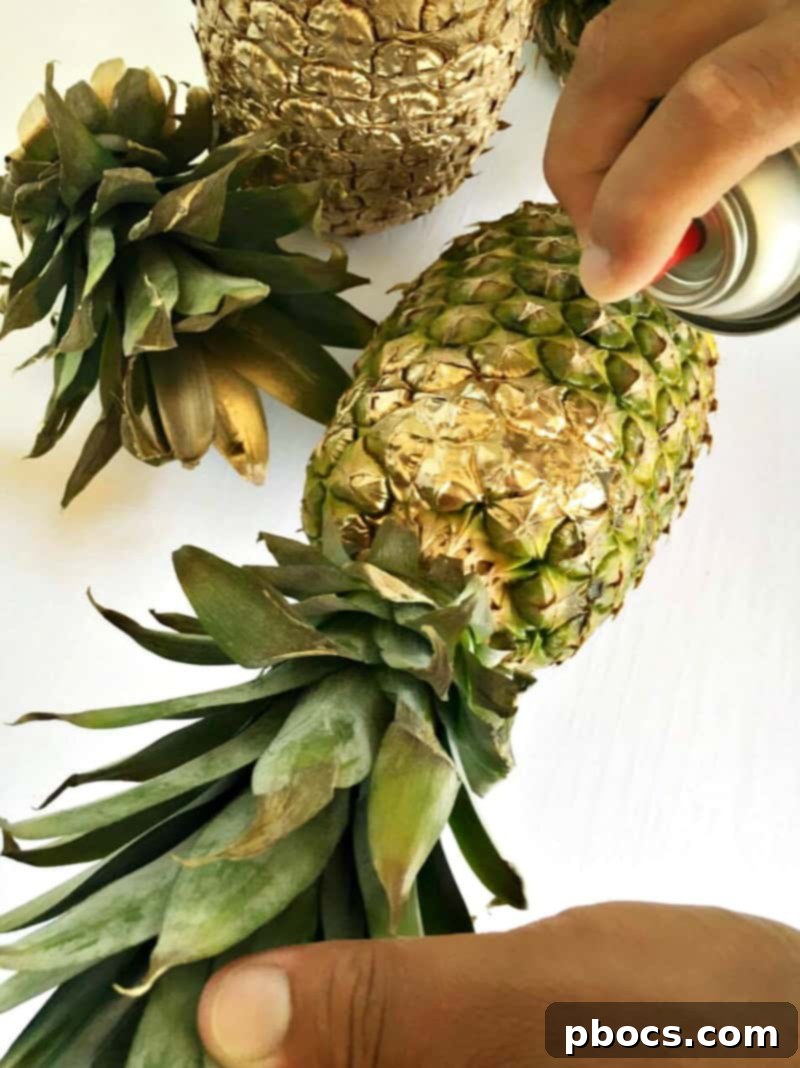 Spray painting a pineapple metallic for a DIY tropical vase.