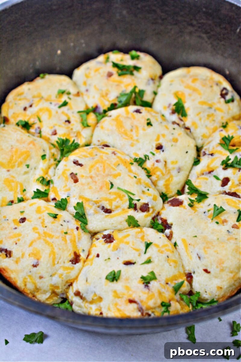 Keto Crave Biscuits 2 Keto Crack Biscuits - A close-up of golden brown biscuits baked in a cast iron skillet, featuring crispy bacon and melted cheese.
