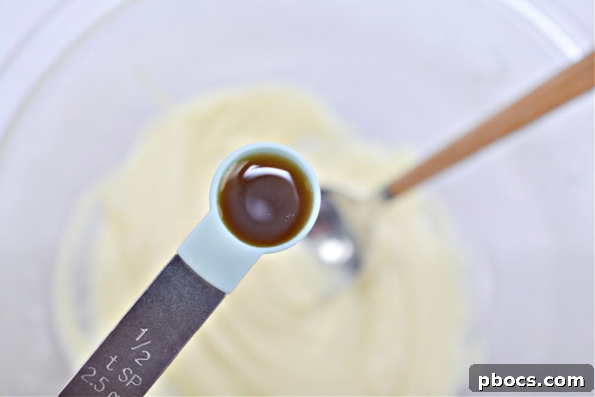Decadent Keto White Chocolate Christmas Shooters 9 Vanilla extract being stirred into melted white chocolate.