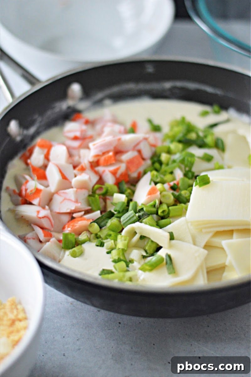 Creamy Keto Crab Rangoon Casserole 11 Thickening sauce in a saucepan