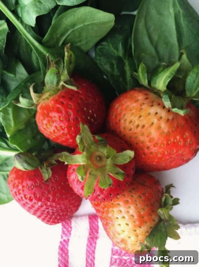 Fresh strawberries, hulled and neatly cut in half, ready to be incorporated into the scallop dish.