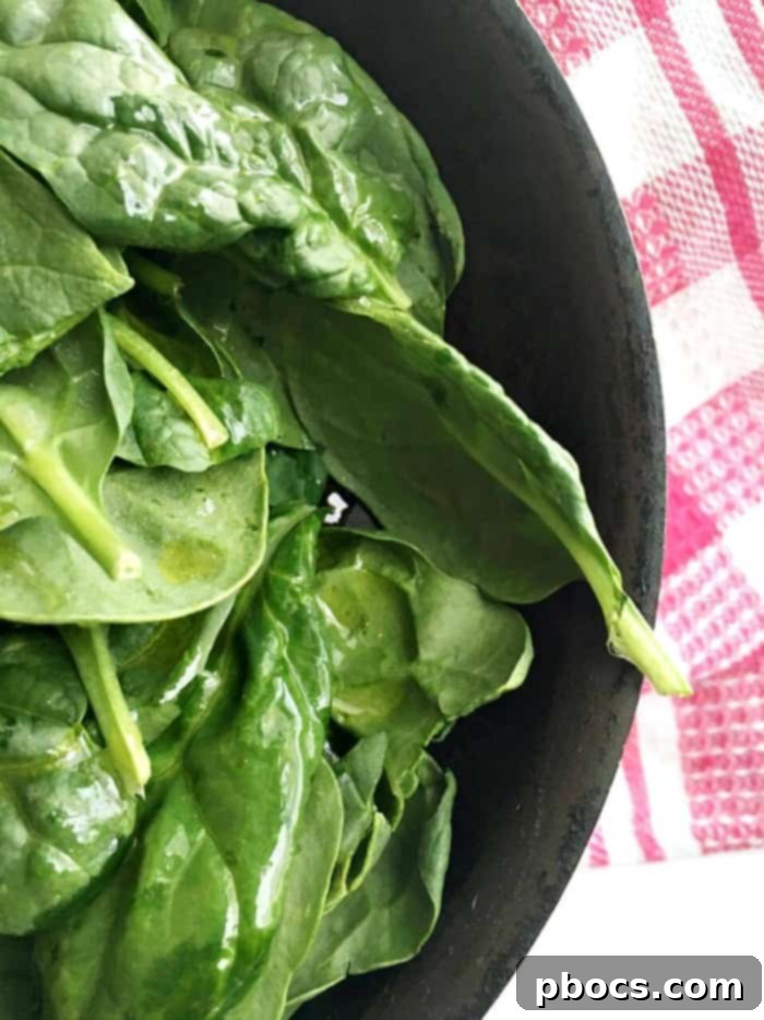 Fresh spinach wilting in a hot skillet with a drizzle of olive oil, becoming tender and vibrant green.