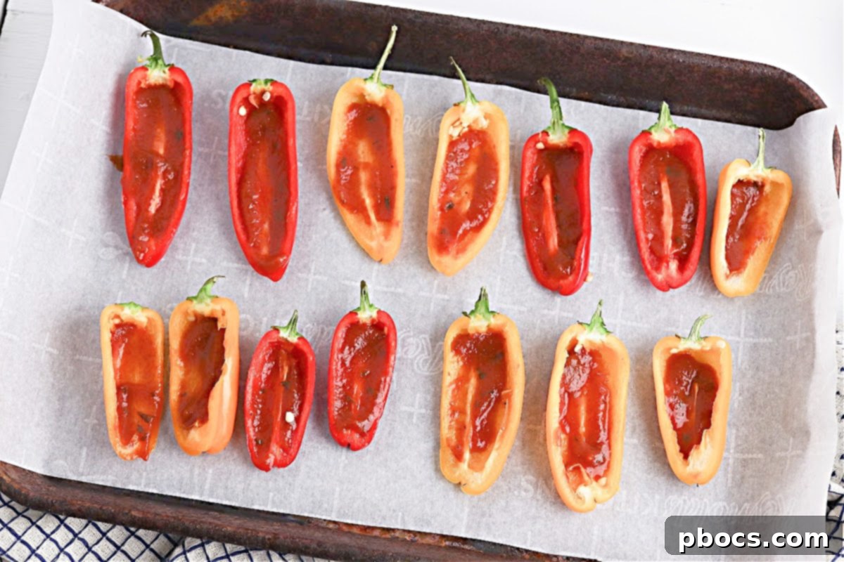 Preparing mini bell peppers on parchment paper on a baking sheet