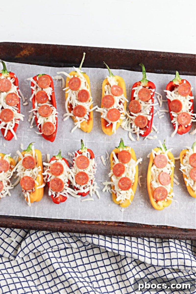 Spreading pizza sauce inside mini bell pepper halves